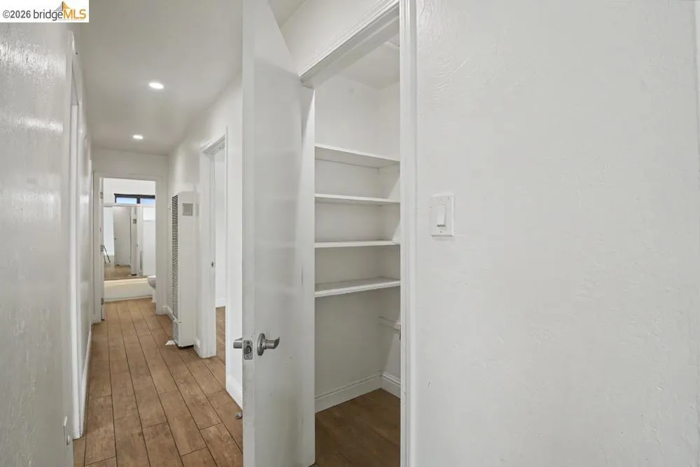 Hallway with wood-finish flooring, recessed lighting, and a built-in shelving unit