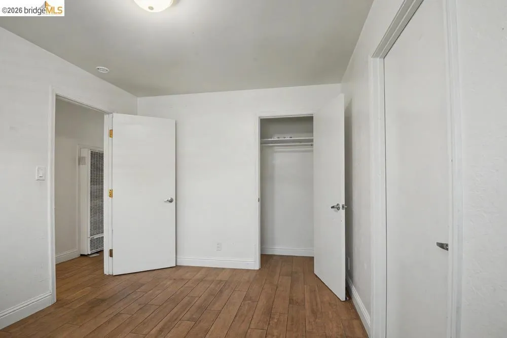 Wood-finish flooring, white walls, and a built-in closet with shelving