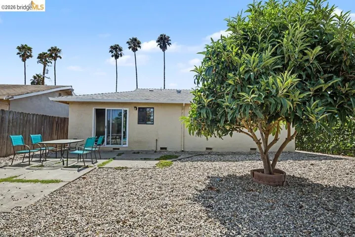Rear exterior featuring a sliding glass door, single window, and gravel landscaping