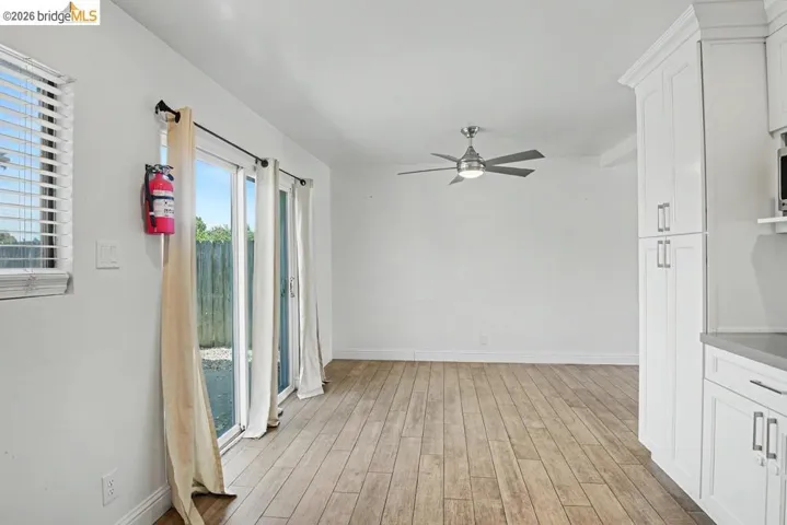 Wood-finish flooring, white cabinetry, a contemporary ceiling fan, and a sliding glass door providing exterior access