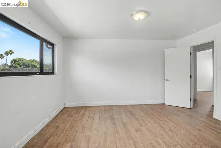 Wood-finish flooring, white walls, black-framed window, flush-mount ceiling light