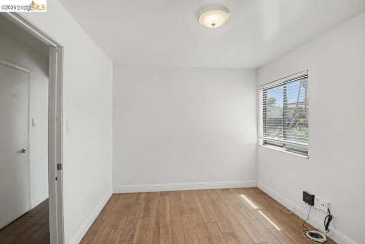 Wood-finish flooring, white walls, and a window with blinds