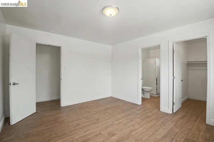 Wood-finish flooring, white walls, flush mount ceiling light, and white interior doors