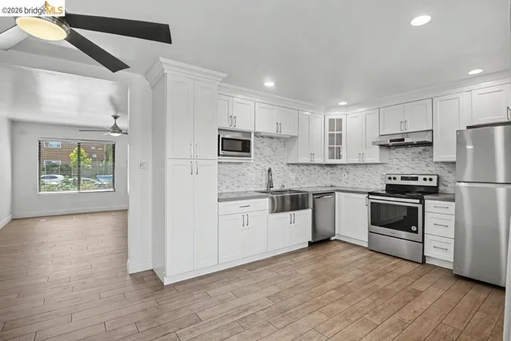 Kitchen featuring white cabinetry, stainless steel appliances, a farmhouse sink, and a tiled backsplash