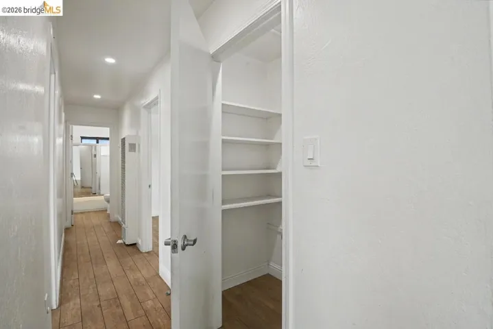 Hallway with wood-finish flooring, recessed lighting, and a built-in shelving unit