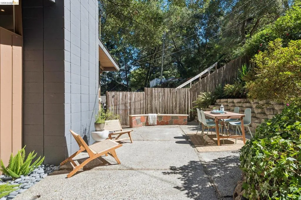 Expansive concrete patio area with a stone veneer retaining wall and mature landscaping