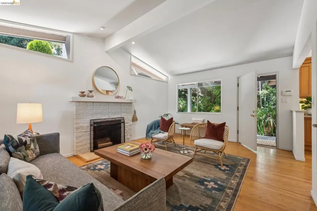 Vaulted ceiling featuring recessed lighting, a fireplace with a tile surround, wood-finish flooring, and multiple windows