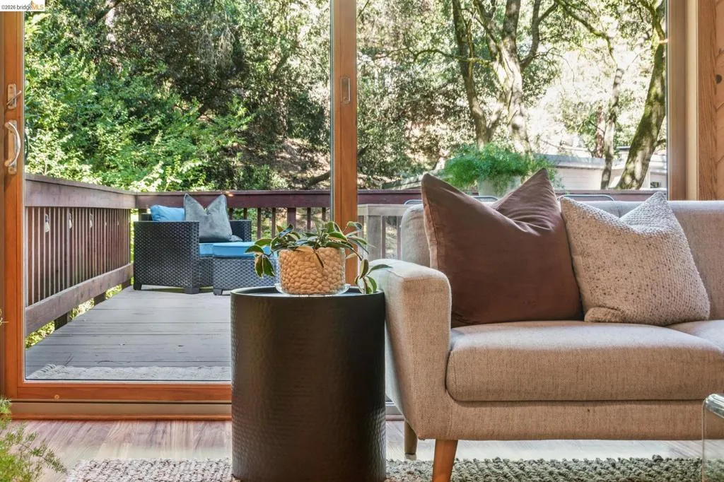 Expansive exterior deck with wood flooring and a protective wood railing, accessed through a large sliding glass door with wood trim