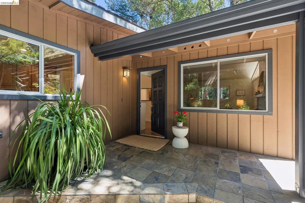 Board-and-batten siding with an inset entry, dark paneled door, and slate tile landing