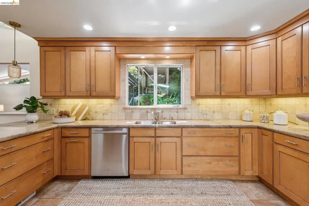 Wrap-around cabinetry with a double basin stainless steel sink, stainless steel dishwasher, and recessed lighting