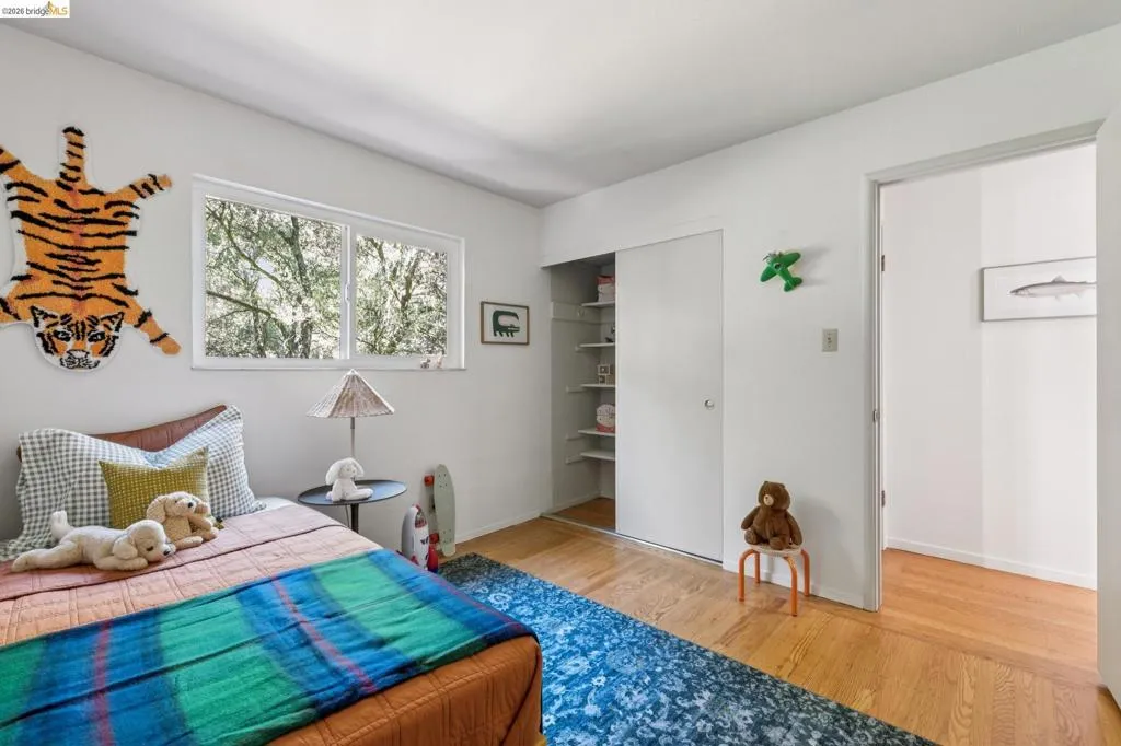 Hardwood flooring, horizontal sliding window, built-in closet with shelving, and white walls