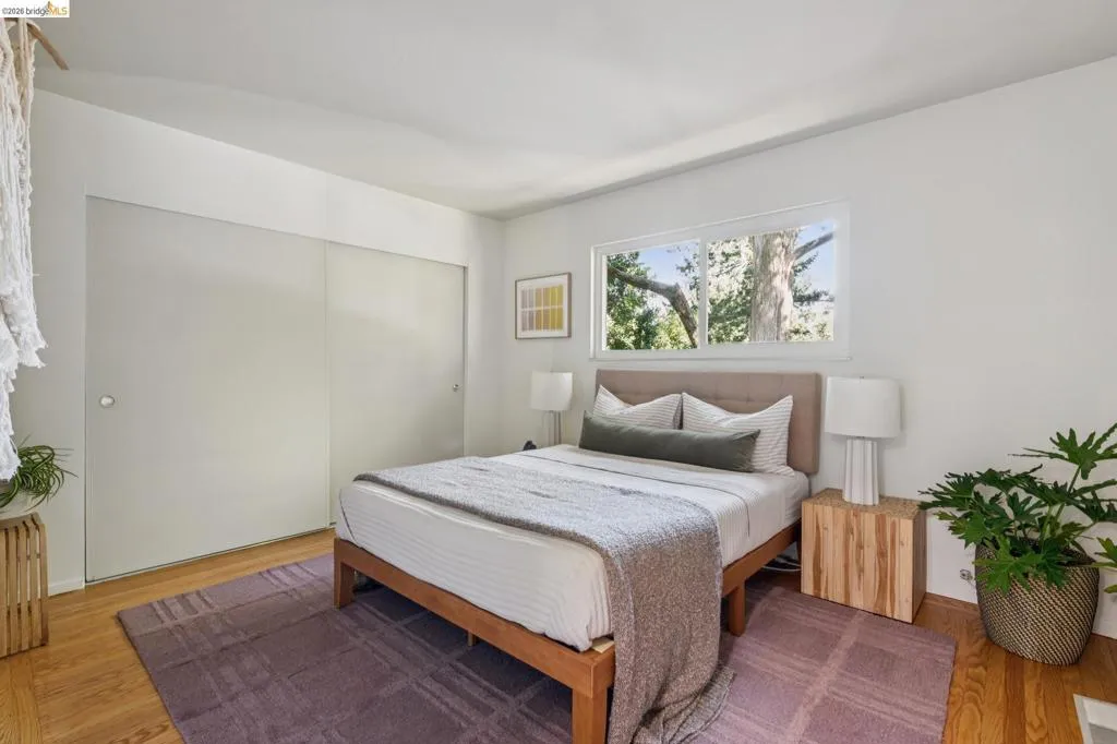 Room featuring hardwood flooring, a horizontal window, and sliding closet doors