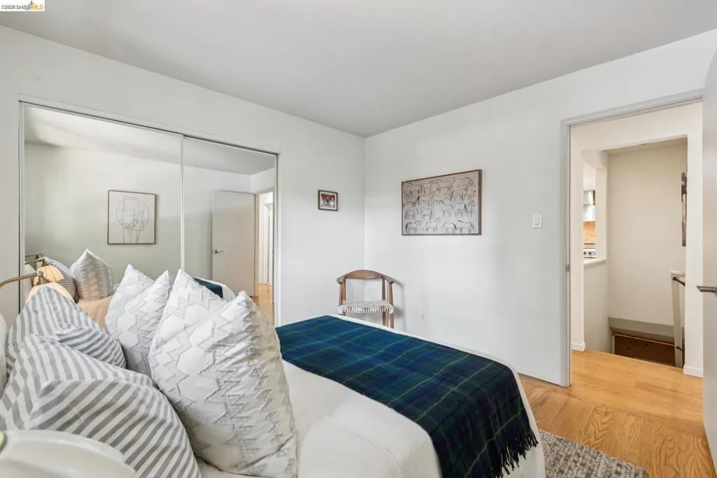 Mirrored sliding closet doors, hardwood-finish flooring, and white wall finishes