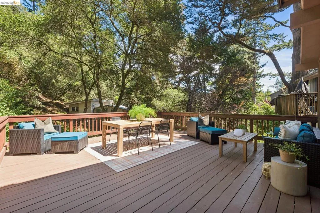 Expansive wooden deck with sturdy railings, surrounded by mature trees