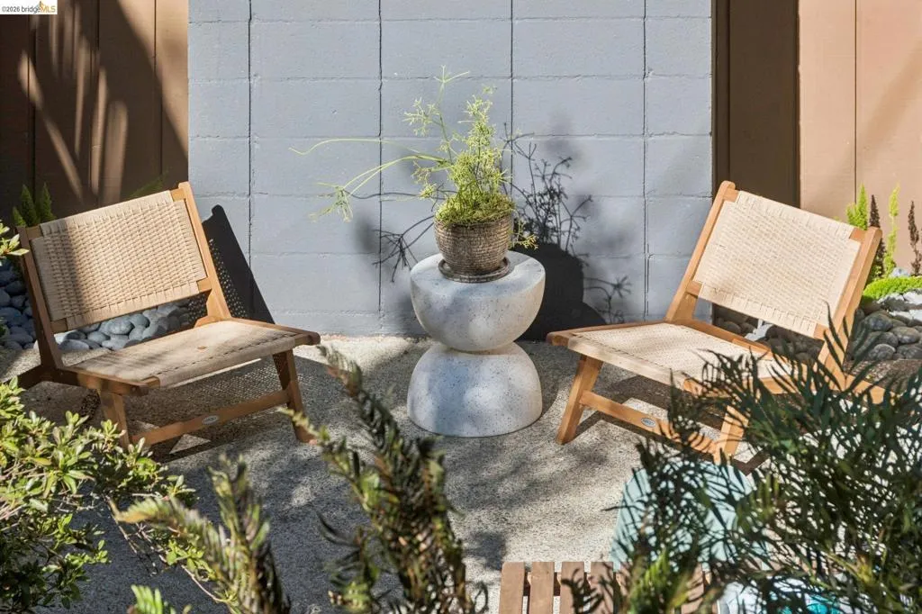 Paved patio area featuring a concrete block wall, planted garden beds, and smooth river stone accents