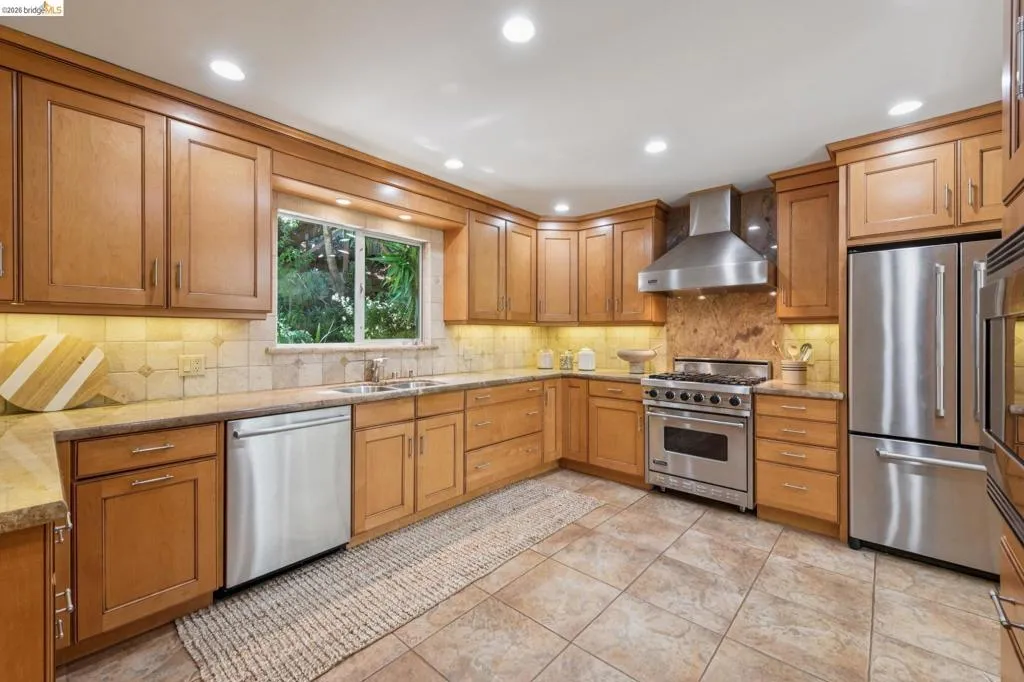 Kitchen featuring wood cabinetry, stainless steel appliances, recessed lighting, tile flooring, and a window over the sink