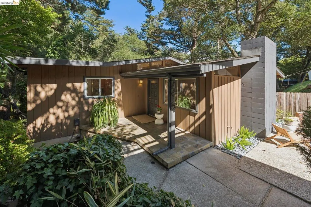 Mid-century modern exterior featuring wood siding, a flat roofline, and an integrated entryway with a covered walkway