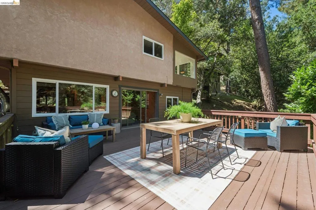 Expansive wood-finish deck with a wood railing, multiple large windows, and a sliding glass door