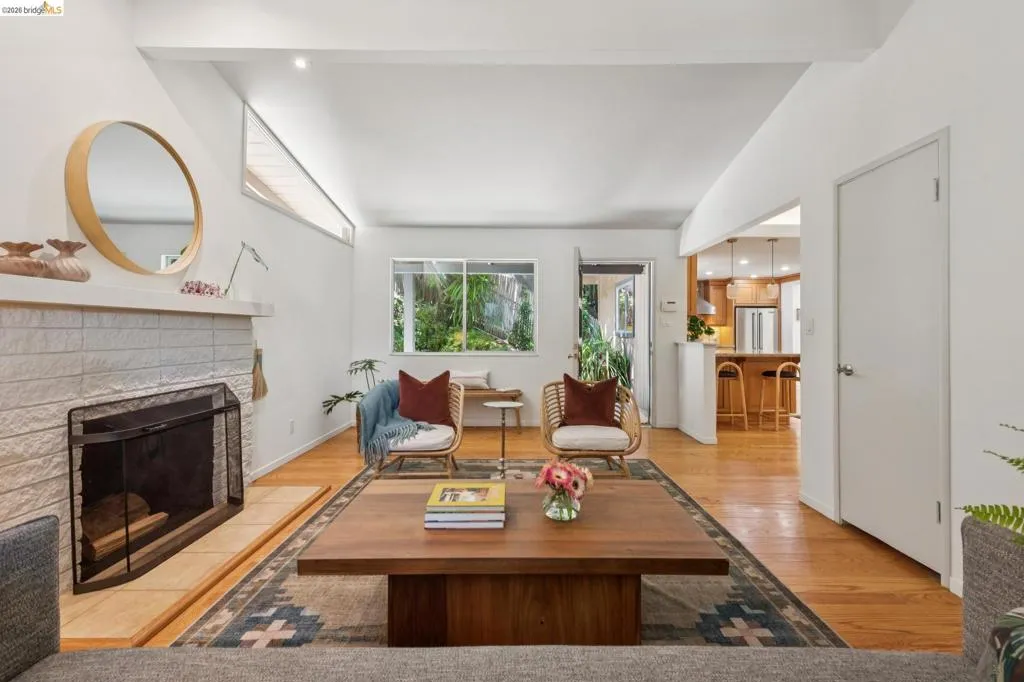 Living area with wood-finish flooring, a white brick fireplace, and recessed lighting