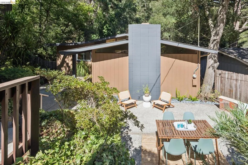 Outdoor patio with gravel hardscaping, a wood slat dining table, and a built-in stone planter