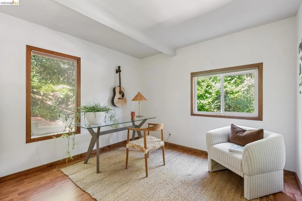 Hardwood-finish flooring, white painted walls, and wood-trimmed windows