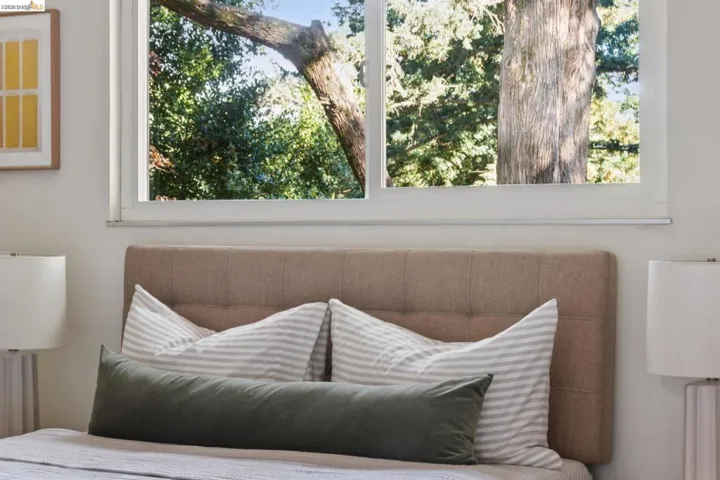 Window with outdoor tree scenery and a tufted upholstered headboard