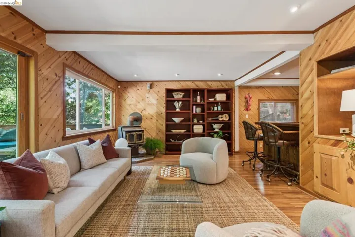 Wood-paneling throughout, built-in shelving, wood-finish flooring, wood-burning stove, and a built-in bar with bar stools