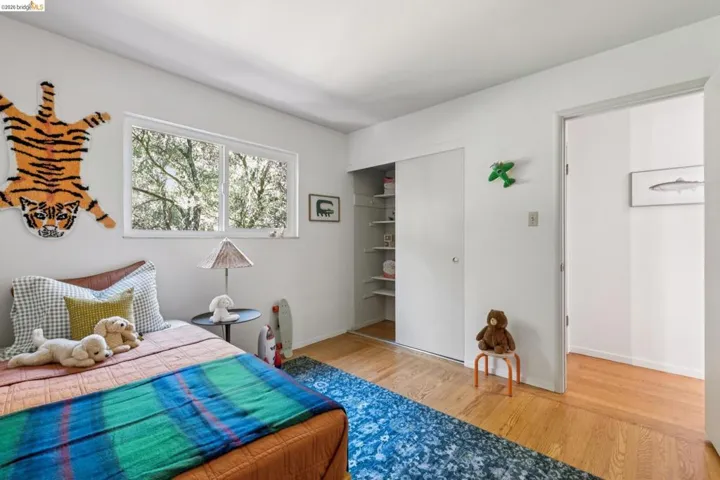 Hardwood flooring, horizontal sliding window, built-in closet with shelving, and white walls