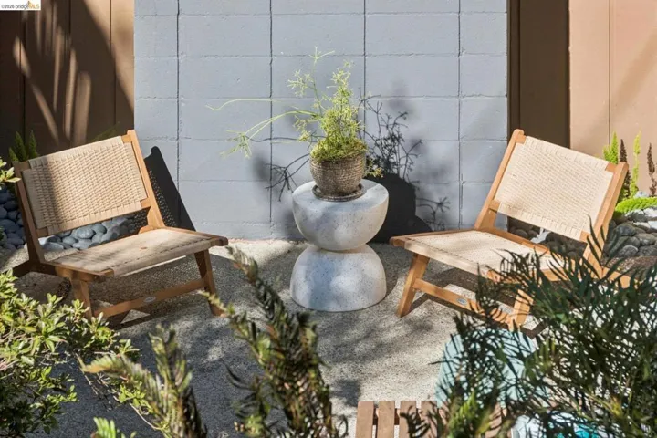 Paved patio area featuring a concrete block wall, planted garden beds, and smooth river stone accents