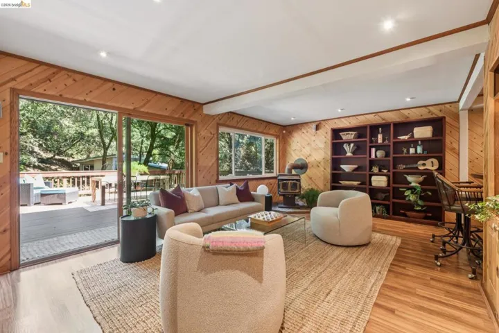 Wood-paneled living area featuring wood-finish flooring, a built-in bookshelf, and a wood-burning stove