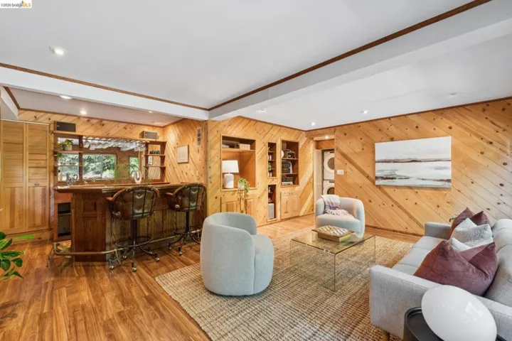 Wood-finish flooring, built-in wet bar with shelving, wood paneling, recessed lighting, and built-in cabinetry