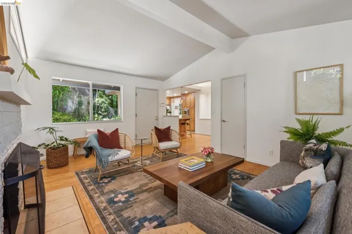 Vaulted ceiling, hardwood flooring, white brick fireplace, sliding window, and recessed lighting