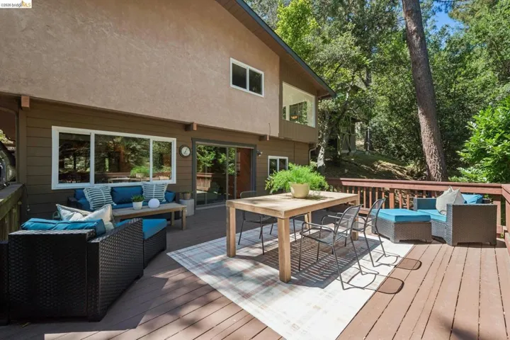 Expansive wood-finish deck with a wood railing, multiple large windows, and a sliding glass door