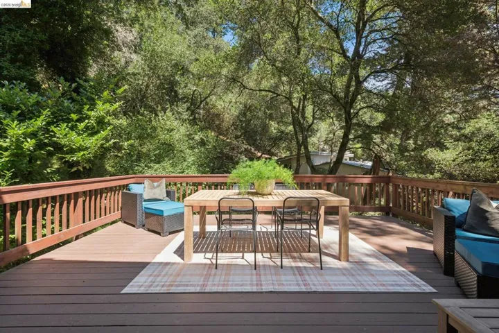 Expansive outdoor deck featuring composite decking, wood railing, and a mature treed backdrop