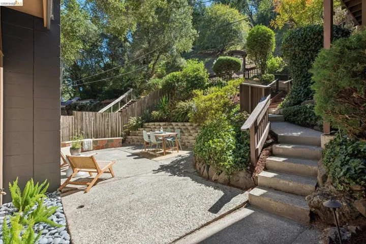 Expansive terraced outdoor area with concrete patio, retaining walls, and established landscaping