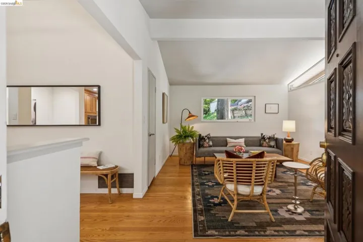 Hardwood flooring throughout, a carved wood entry door, and an expansive living area with natural light from a horizontal window