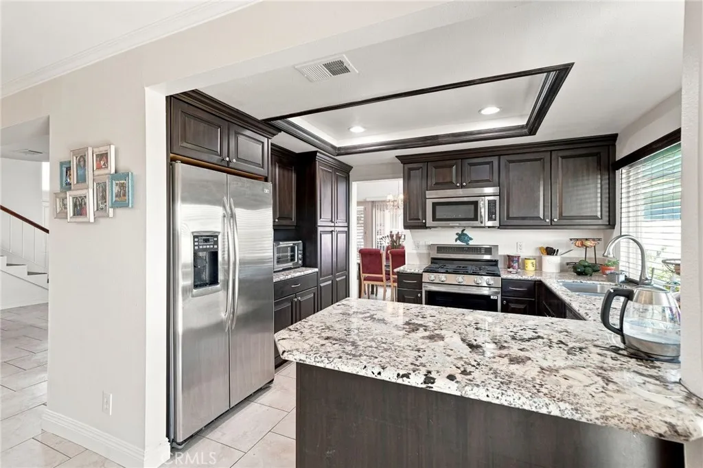 The upgraded kitchen features attractive granite countertops, rich wood cabinetry, stainless steel appliances, recessed lighting, and a large breakfast counter all highlighted The upgraded kitchen features attractive granite countertops, rich wood cabinetry, stainless steel appliances, recessed lighting, and a large breakfast counter all highlighted