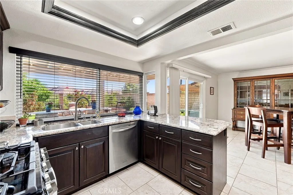 The upgraded kitchen features attractive granite countertops, rich wood cabinetry, stainless steel appliances, recessed lighting, and a large breakfast counter all highlighted with an oversized window overlooking the backyard and surrounding scenery. The upgraded kitchen features attractive granite countertops, rich wood cabinetry, stainless steel appliances, recessed lighting, and a large breakfast counter all highlighted with an oversized window overlooking the backyard and surrounding scenery.