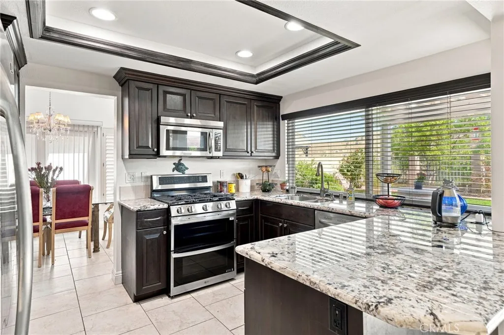 The upgraded kitchen features attractive granite countertops, rich wood cabinetry, stainless steel appliances, recessed lighting, and a large breakfast counter all highlighted with an oversized window overlooking the backyard and surrounding scenery. The upgraded kitchen features attractive granite countertops, rich wood cabinetry, stainless steel appliances, recessed lighting, and a large breakfast counter all highlighted with an oversized window overlooking the backyard and surrounding scenery.