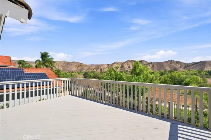 The spacious primary suite offers a direct access to a large private balcony deck with spectacular panoramic views of the surrounding hills and natural open space.