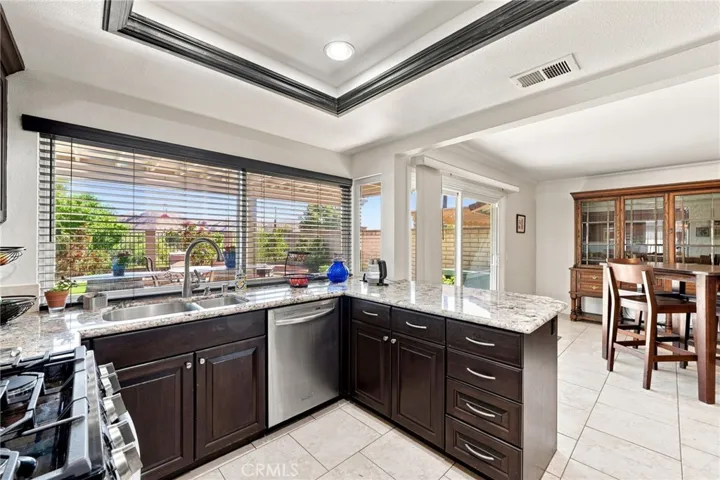 The upgraded kitchen features attractive granite countertops, rich wood cabinetry, stainless steel appliances, recessed lighting, and a large breakfast counter all highlighted with an oversized window overlooking the backyard and surrounding scenery.