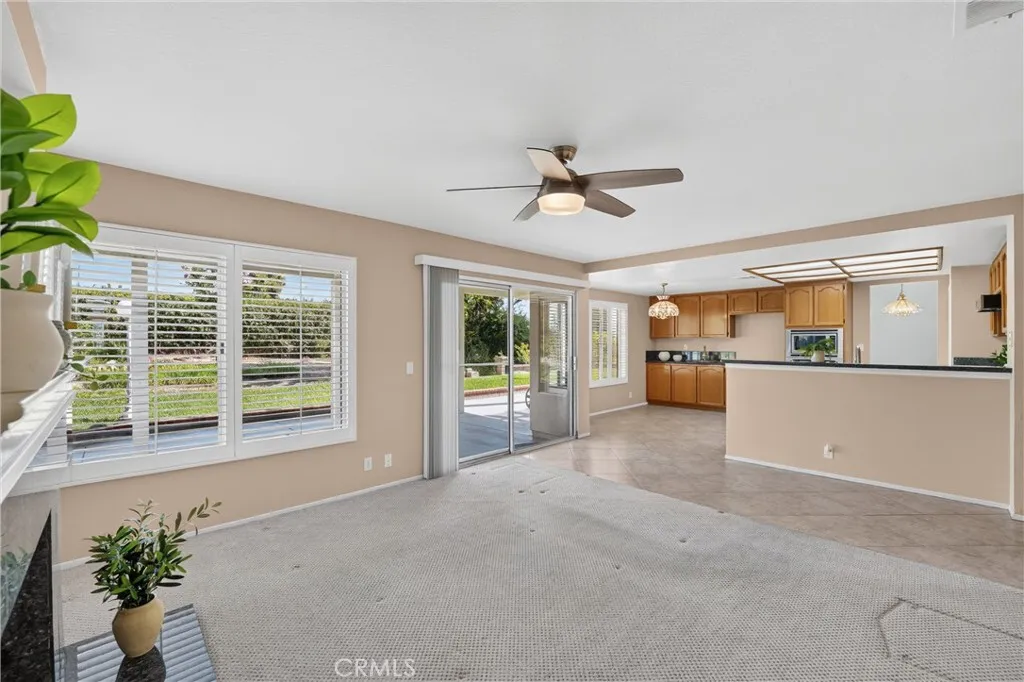 Plantation Shutters, Ceiling Fan and view into kitchen, view of the outdoors.