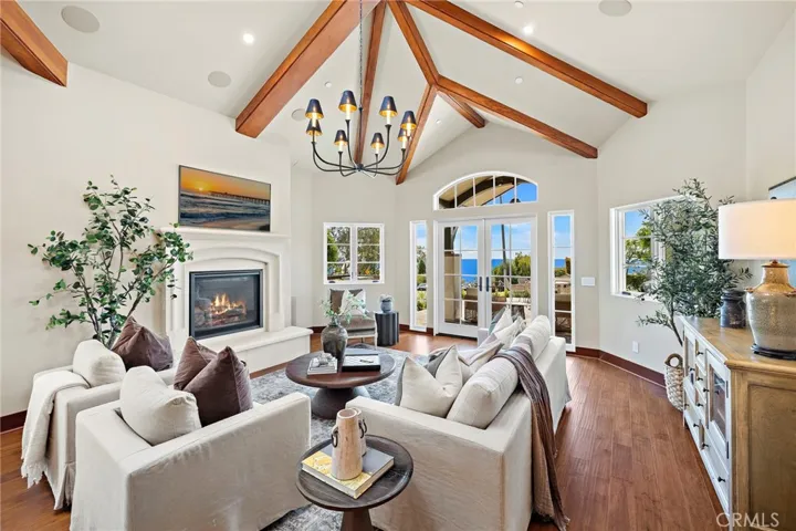 Living room with soaring ceilings and distressed maple hardwood flooring that extends throughout the home, complemented by a gas fireplace with a Veristone surround.