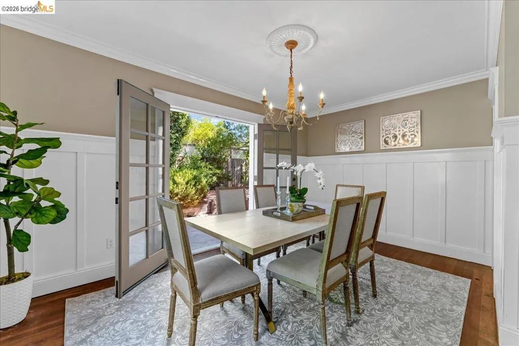 Hardwood flooring, crown molding, wainscoting, french doors, and a decorative ceiling medallion with a chandelier