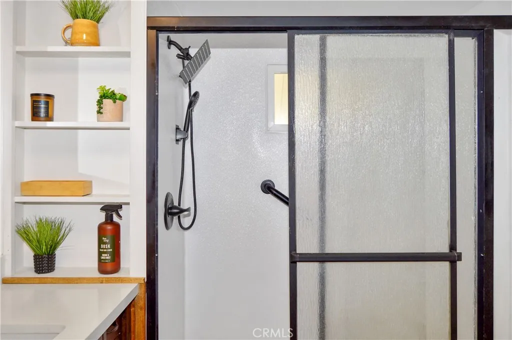 Remodeled Bath with Glass-Enclosed Shower Stall, Furniture-Style Vanity with Stylish Square Sink, Framed Mirror, Open Shelving, Modern Black Fixtures, and a Bidet Remodeled Bath with Glass-Enclosed Shower Stall, Furniture-Style Vanity with Stylish Square Sink, Framed Mirror, Open Shelving, Modern Black Fixtures, and a Bidet