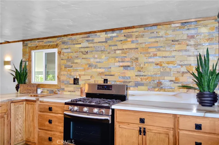 Big, Beautiful Kitchen with New Cabinetry, Quartz Countertops, Stainless Steel Sink with Sprayer, Stainless Steel and Black Range, Wood and Stone Accents, Custom Lighting, Black Hardware, and a Wood-Trimmed Refrigerator