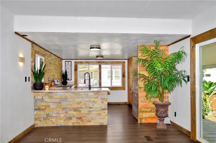 Big, Beautiful Kitchen with New Cabinetry, Quartz Countertops, Stainless Steel Sink with Sprayer, Stainless Steel and Black Range, Wood and Stone Accents, Custom Lighting, Black Hardware, and a Wood-Trimmed Refrigerator