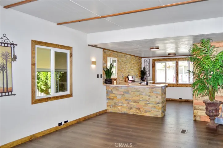 Great-Room-Style Living Open to Kitchen with Rich, Dark, Wood-Look Laminate Flooring, Lighter Wood Accents and Island-Themed Decor - All Included for Your Enjoyment