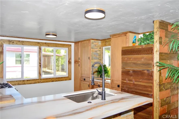 Big, Beautiful Kitchen with New Cabinetry, Quartz Countertops, Stainless Steel Sink with Sprayer, Stainless Steel and Black Range, Wood and Stone Accents, Custom Lighting, Black Hardware, and a Wood-Trimmed Refrigerator