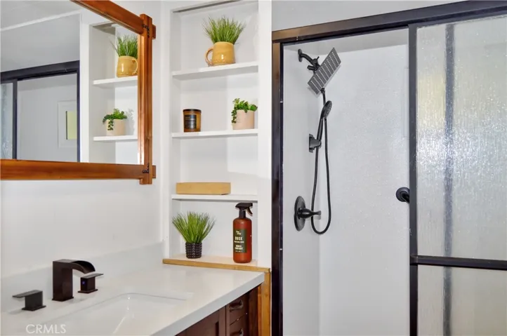 Remodeled Bath with Glass-Enclosed Shower Stall, Furniture-Style Vanity with Stylish Square Sink, Framed Mirror, Open Shelving, Modern Black Fixtures, and a Bidet